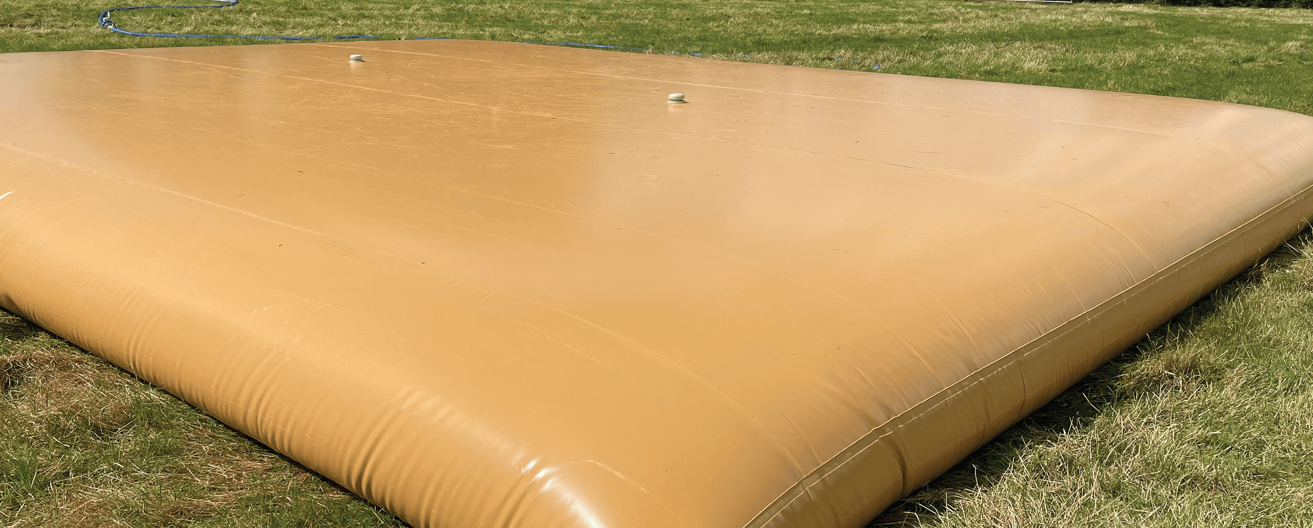 Image of flexible water bladder in a green field.